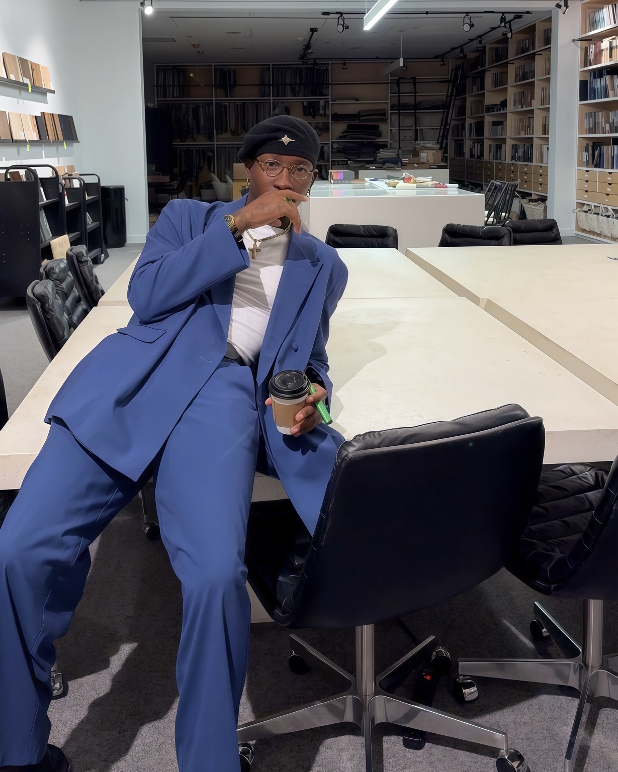 Claudio Conde de fato azul sentado num espaço de criação